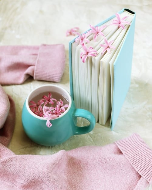 A close-up image showing a stack of romance novels with soft, pastel-colored covers. The books are arranged neatly, and a delicate flower is placed on top, symbolizing the romance genre.