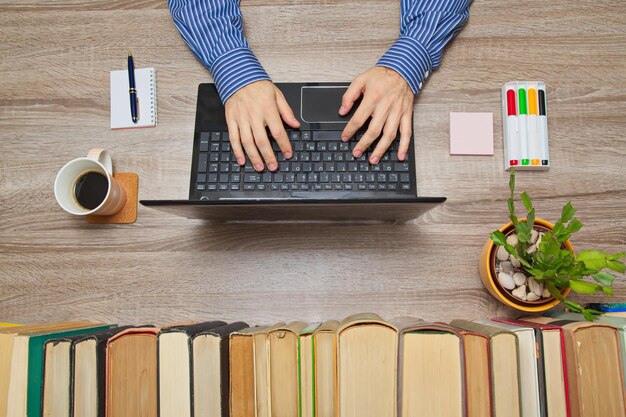 A person sitting at a desk, surrounded by books, examining a laptop screen displaying a book review website. Their expression is thoughtful and analytical, indicating they are carefully considering the different opinions presented in the reviews.