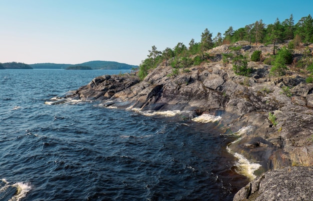 A panoramic shot of the Maine coastline, with rocky cliffs, crashing waves, and a dense forest in the background. The image captures the rugged beauty and isolation of the Maine landscape that frequently inspires Stephen King's stories.