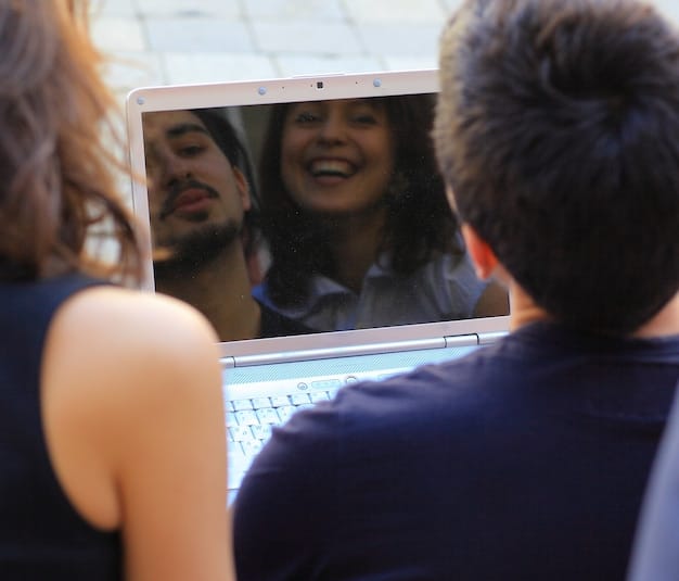 A close-up of a laptop screen showcasing a virtual book club meeting on Zoom. Participants are shown in individual boxes, smiling and actively engaged in the discussion. The screen also displays shared notes and a poll question.