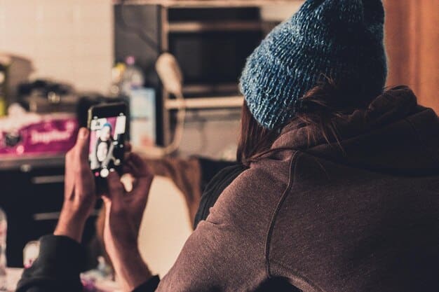 A close-up shot of a smartphone camera being used to photograph an author at a book signing. The author is signing a book, and the smartphone displays the camera interface with various manual settings. The background is slightly blurred, emphasizing the author and the phone.