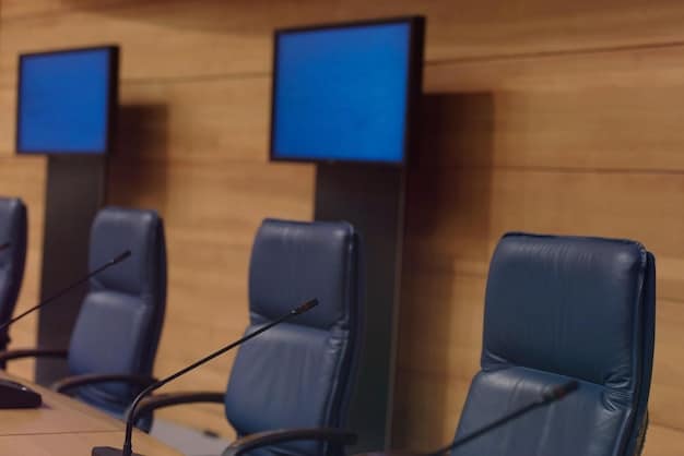 A well-equipped conference room with a large screen displaying a presentation, microphones set up on a podium, and attendees seated comfortably.