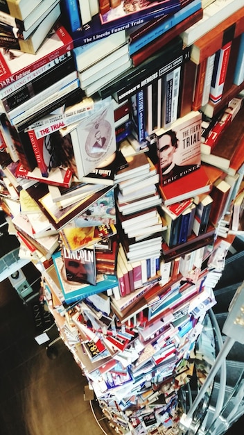 A stack of diverse books with various genres, including fiction, non-fiction and memoirs, with titles subtly hinting at social justice and environmental themes, on a rustic wooden table with a 'Book Club' mug.