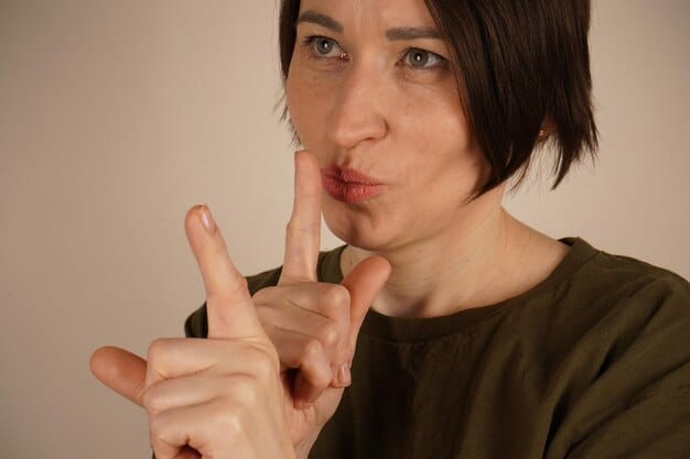 A close-up of a person's mouth with a finger over their lips, indicating silence, set against a blurred background of a group of people, symbolizing the importance of not interrupting or dominating conversations.