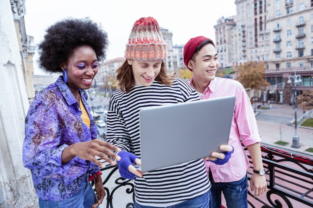 A diverse group of people from different global locations enthusiastically participating in a hybrid online and in-person book club meeting, with screens for virtual attendees integrated seamlessly with the physical gathering.