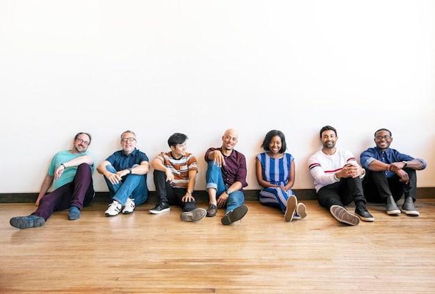 A diverse group of people, representing different ages and ethnic backgrounds, are seated around a large circular table in a vibrant, modern coworking space. They are collaboratively sketching ideas on a large blueprint laid out on the table, with some pointing to different sections and others leaning in to contribute. Laptops and coffee mugs are interspersed with creative tools like markers and Post-it notes. Sunlight streams in through large windows, illuminating the energetic atmosphere.