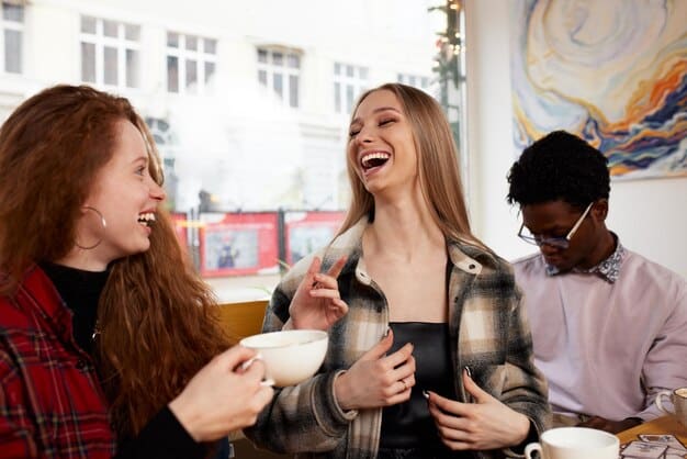 A group of friends laughing and pointing at passages in a book during a lively book club meeting at a cafe, with coffee cups and comfortable attire.