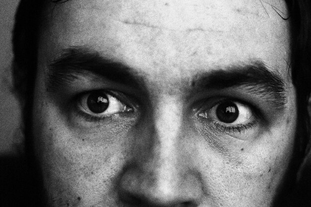 A close-up shot of a person's eye, wide with terror, reflecting a distorted, barely visible figure in the pupil, symbolizing internal fear.