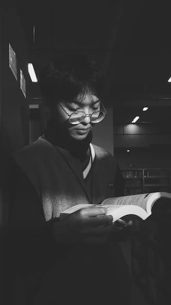 A black and white photograph of a person reading a book intensely, with the light highlighting the pages. The background is blurred, suggesting a focus on the act of reading and immersion in the story.