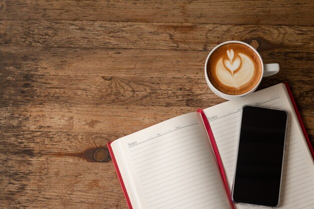 An overhead shot of a desk with a book, a cup of coffee, and a laptop. The laptop screen displays a document with a book review in progress. The scene suggests a writer at work, carefully crafting their critique and immersed in the process of The Art of the Book Review: A Guide for Aspiring Critics in the US.